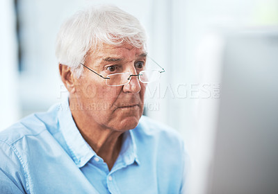 Buy stock photo Cropped shot of a handsome senior businessman working on his computer at home