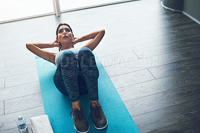 Buy stock photo Shot of an attractive young woman doing sit ups in a gym