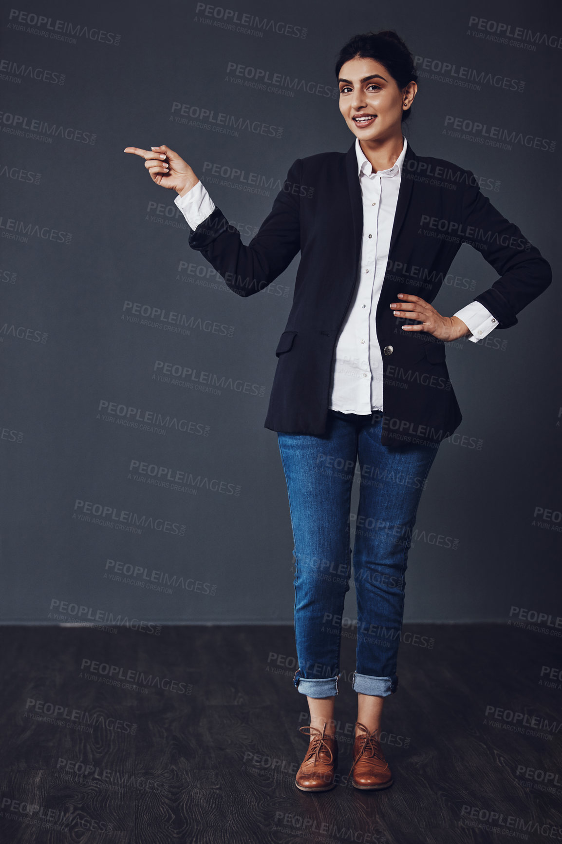 Buy stock photo Studio shot of an attractive young businesswoman pointing at copy space against a dark background