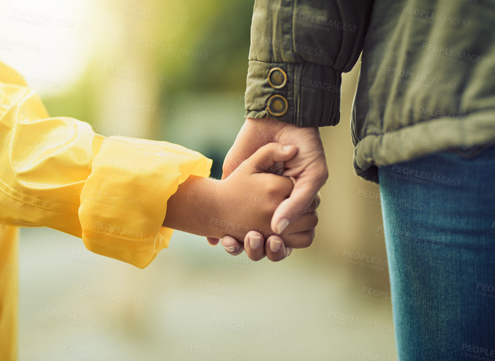 Buy stock photo Closeup shot of an unrecognizable little boy and his mother holding hands in the rain outside
