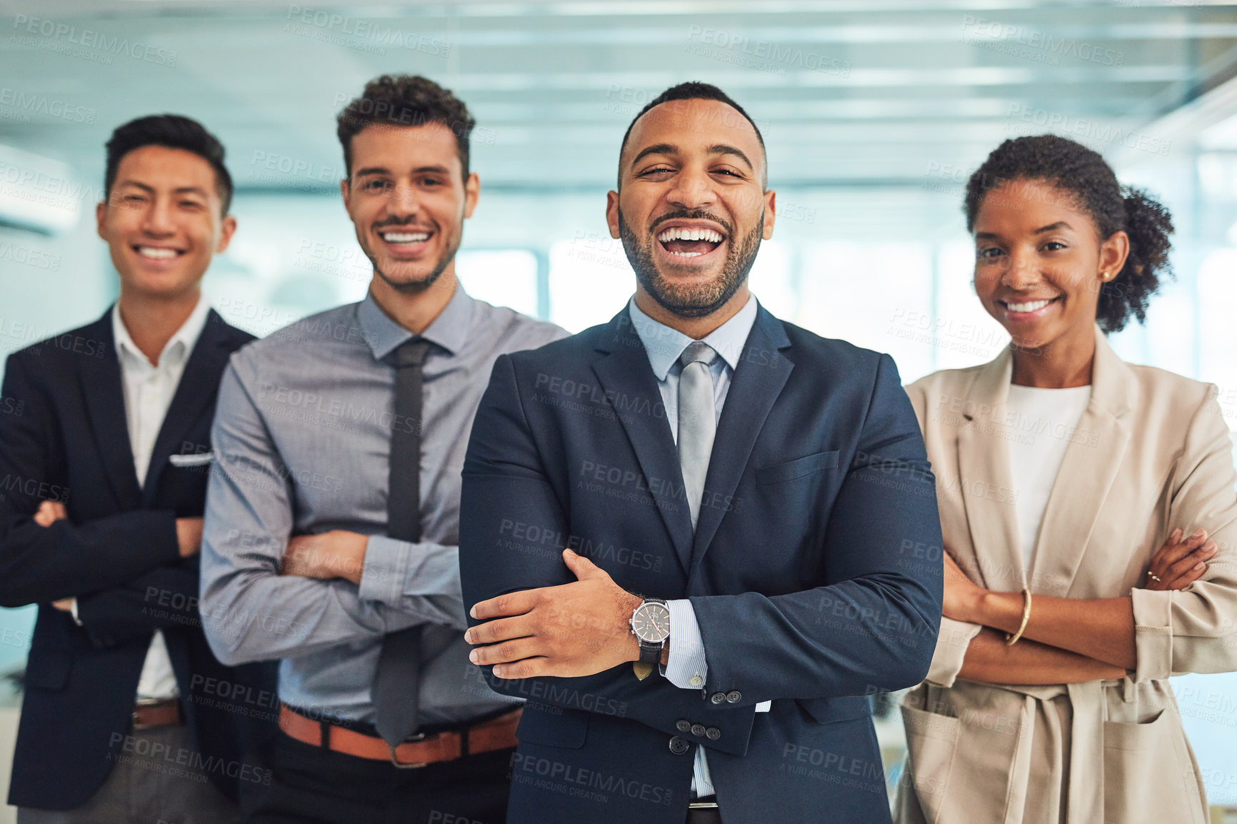 Buy stock photo Portrait of a group of cheerful young businesspeople standing with their arms folded in the office during the day