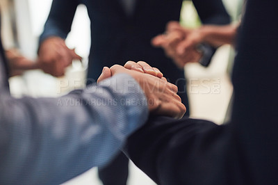 Buy stock photo Closeup of a group of unrecognizable businesspeople holding hands while standing in circle in the office during the day