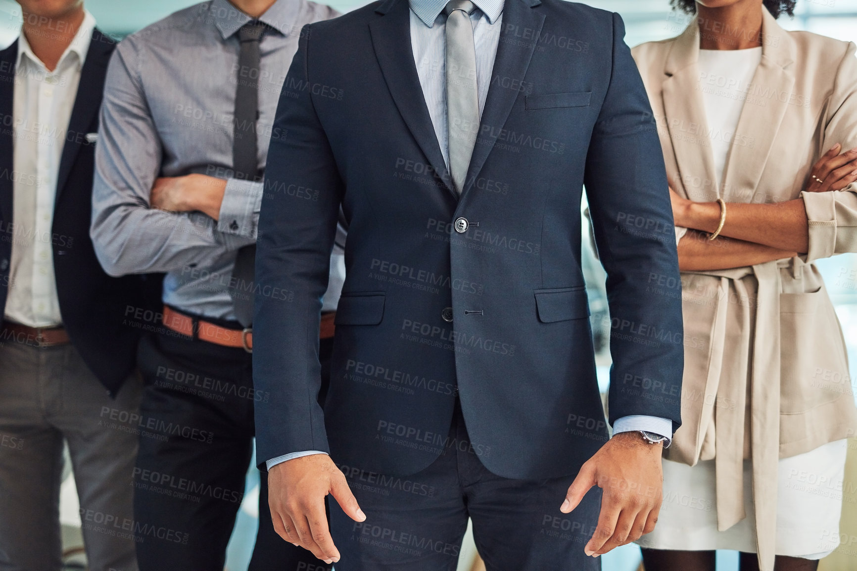 Buy stock photo Shot of a group of unrecognizable businesspeople standing with their arms folded inside of the office at work during the day