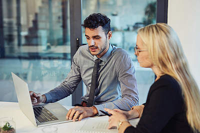Buy stock photo Shot of a young businessman and businesswoman using a laptop together during a meeting in a modern office