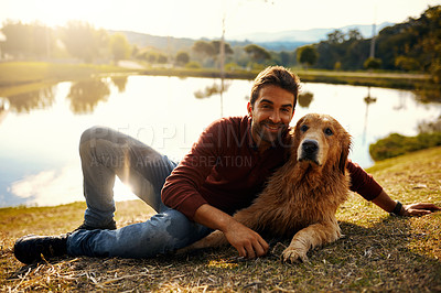 Buy stock photo Full length portrait of a handsome young man and his dog spending the day by a lake in the park