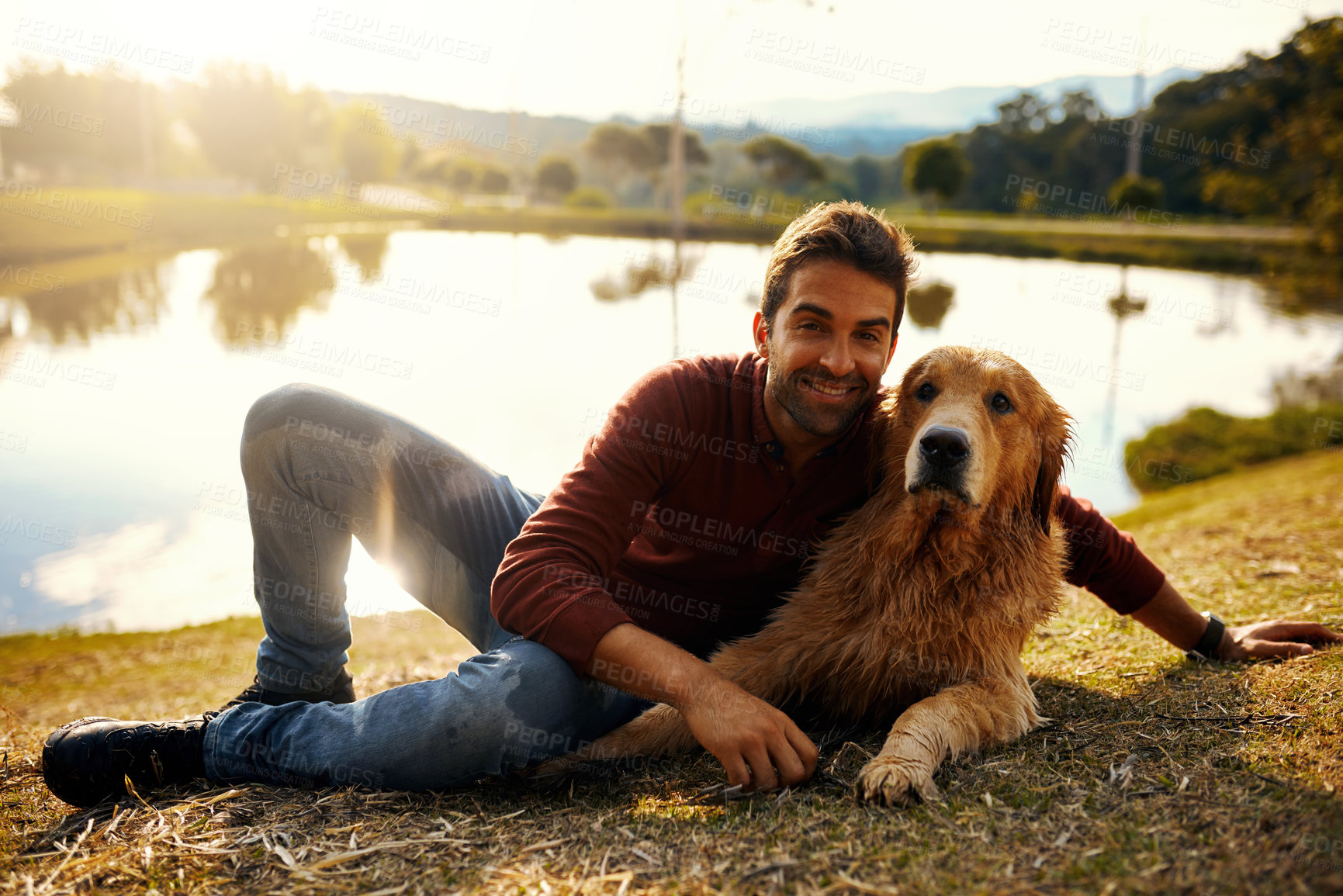 Buy stock photo Full length portrait of a handsome young man and his dog spending the day by a lake in the park