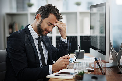 Buy stock photo Shot of a young businessman looking stressed out while working in an office