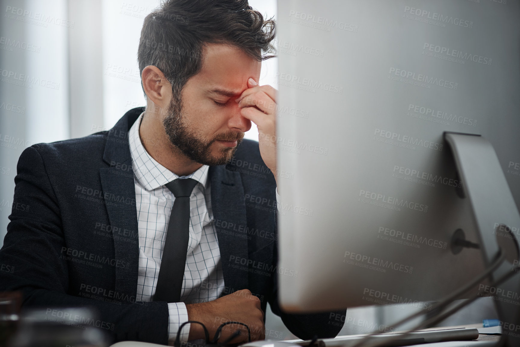 Buy stock photo Shot of a young businessman suffering with a headache while working in an office