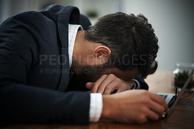 Buy stock photo Shot of a young businessman lying with his head down on a laptop in an office