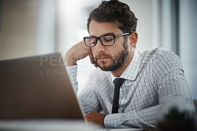 Buy stock photo Shot of a young businessman looking bored while working in an office