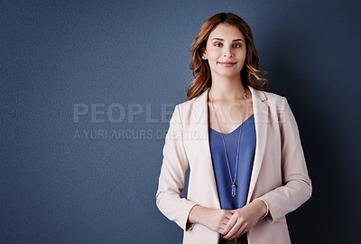 Buy stock photo Studio portrait of an attractive and confident young businesswoman posing against a dark blue background