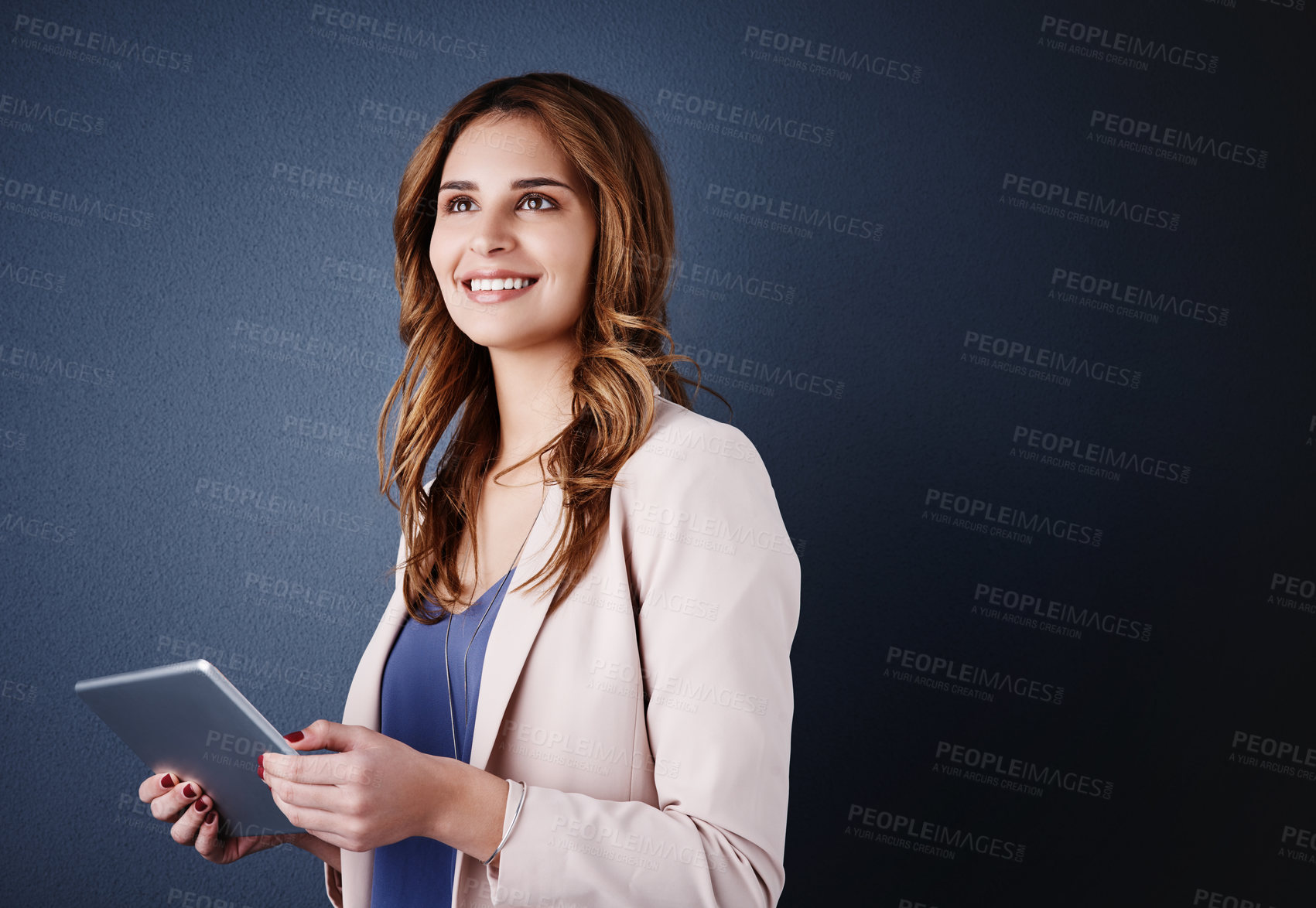 Buy stock photo Studio shot of an attractive young businesswoman using a digital tablet against a dark blue background