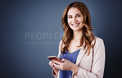Buy stock photo Studio portrait of an attractive young businesswoman using a mobile phone against a dark blue background