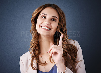Buy stock photo Studio shot of an attractive young businesswoman looking thoughtful against a dark blue background