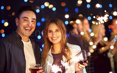 Buy stock photo Portrait of an attractive young couple having fun with sparklers at a nightclub