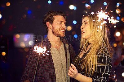 Buy stock photo Cropped shot of an attractive young couple having fun with sparklers at a nightclub