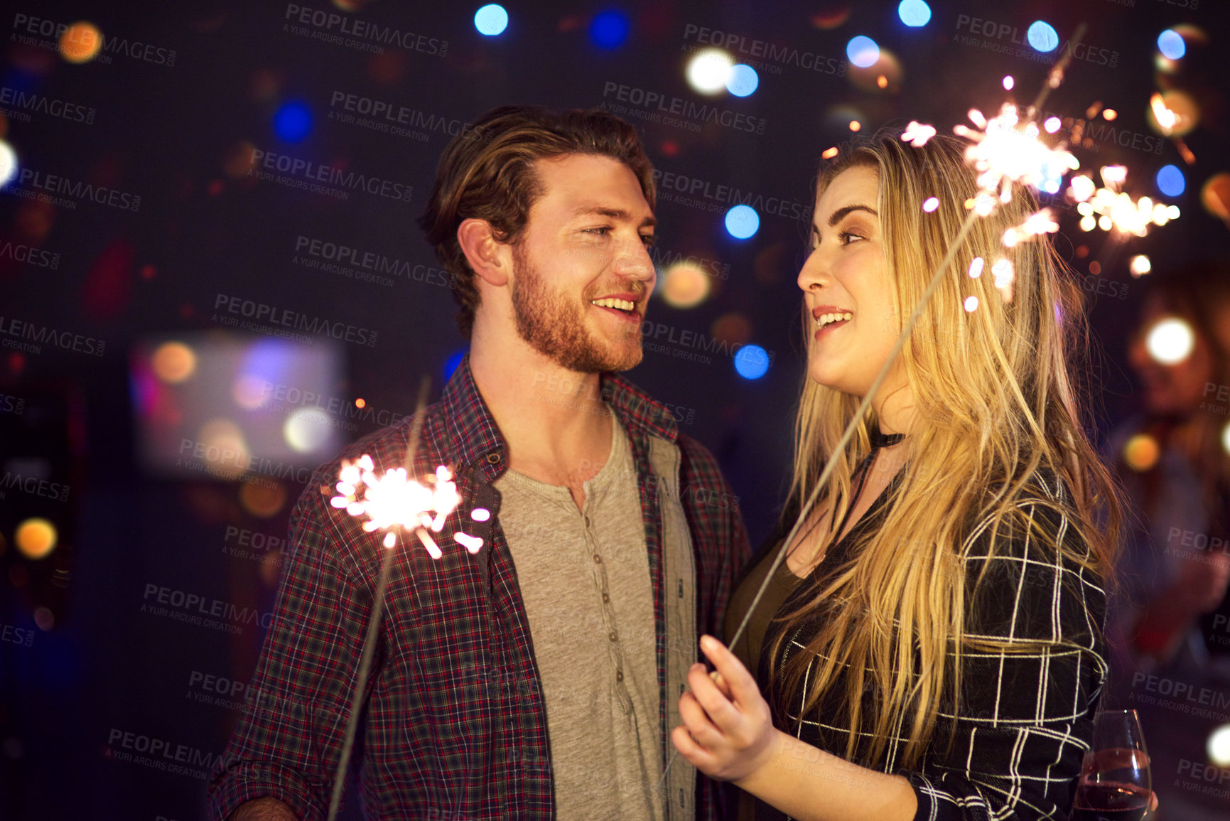 Buy stock photo Cropped shot of an attractive young couple having fun with sparklers at a nightclub