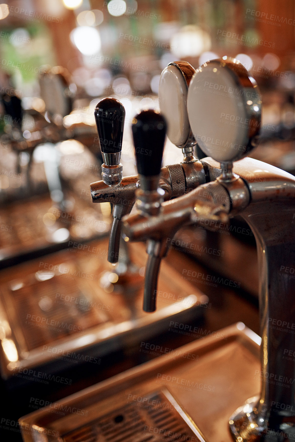Buy stock photo Closeup of a couple of beer taps standing and waiting to be used inside of a beer brewery during the day