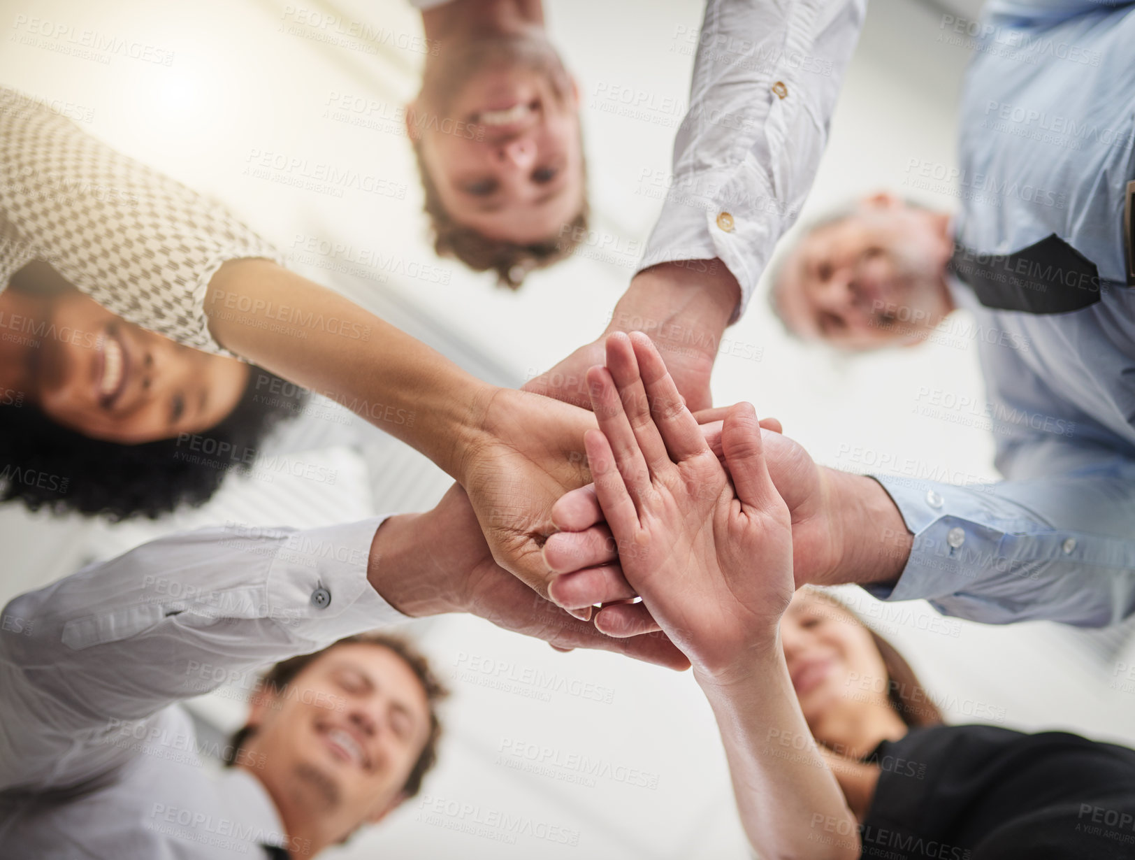 Buy stock photo Low angle shot of a group of colleagues joining hands in solidarity in a modern office