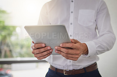 Buy stock photo Cropped shot of an unrecognizable businessman using a digital tablet in a modern office