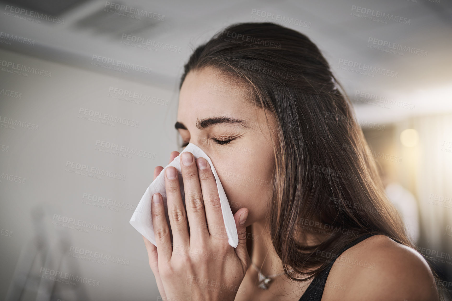 Buy stock photo Shot of a young woman blowing her nose
