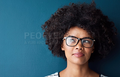 Buy stock photo Studio shot of an attractive young woman looking thoughtful against a blue background