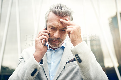 Buy stock photo Shot of a mature businessman looking stressed out while talking on a cellphone in the city