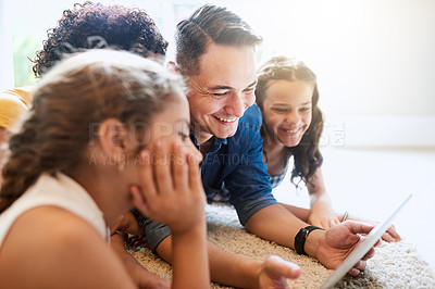 Buy stock photo Cropped shot of a young family of four looking at a tablet while sitting on the sofa at home