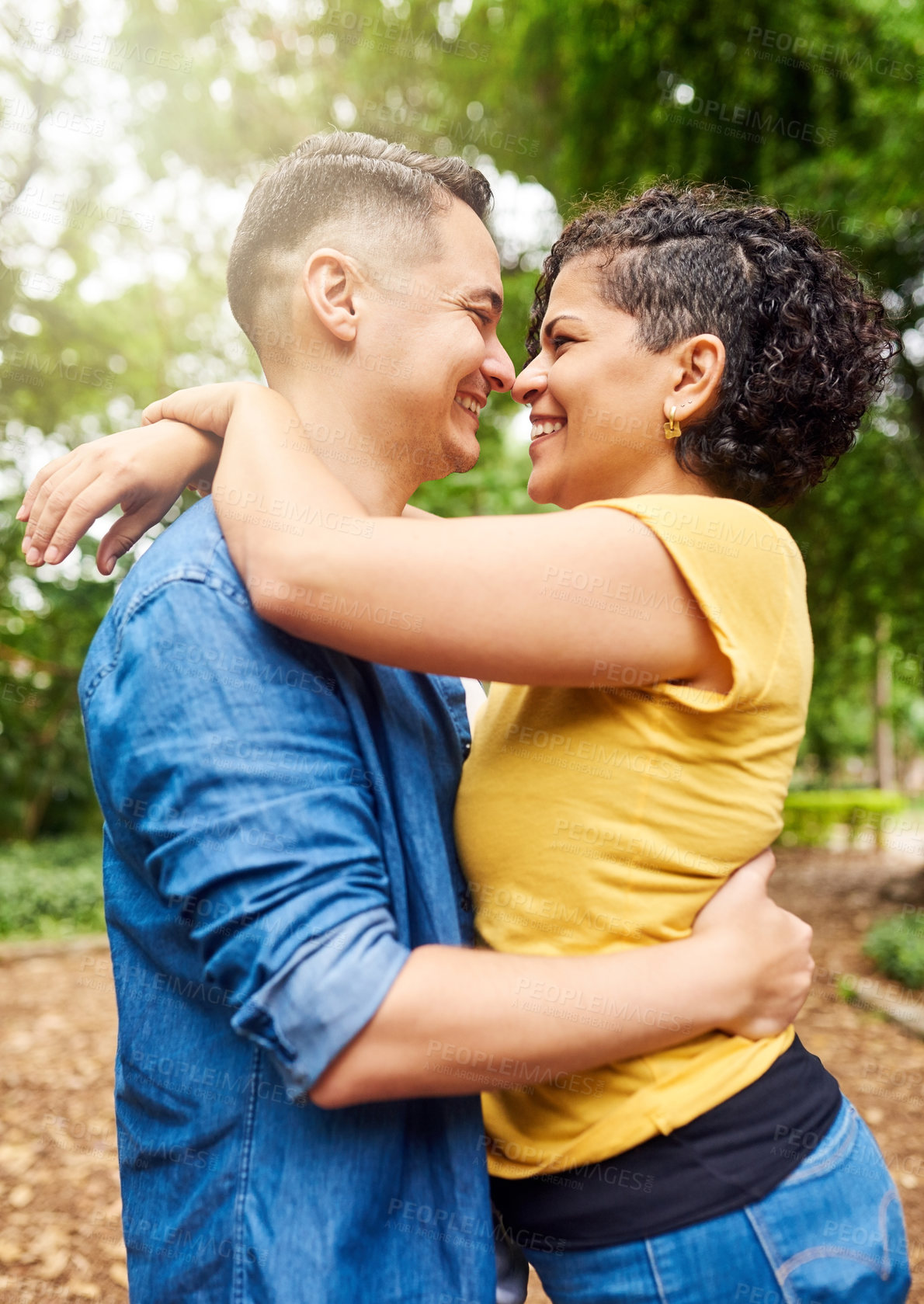 Buy stock photo Cropped shot of an affectionate young couple embracing while standing outside in the park