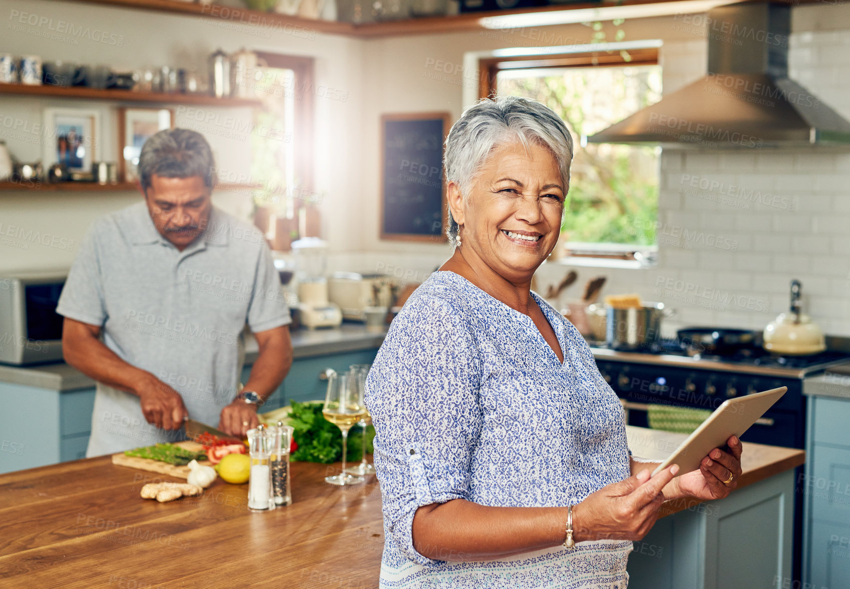 Buy stock photo Portrait of a mature woman using a digital tablet while preparing a meal at home with her husband