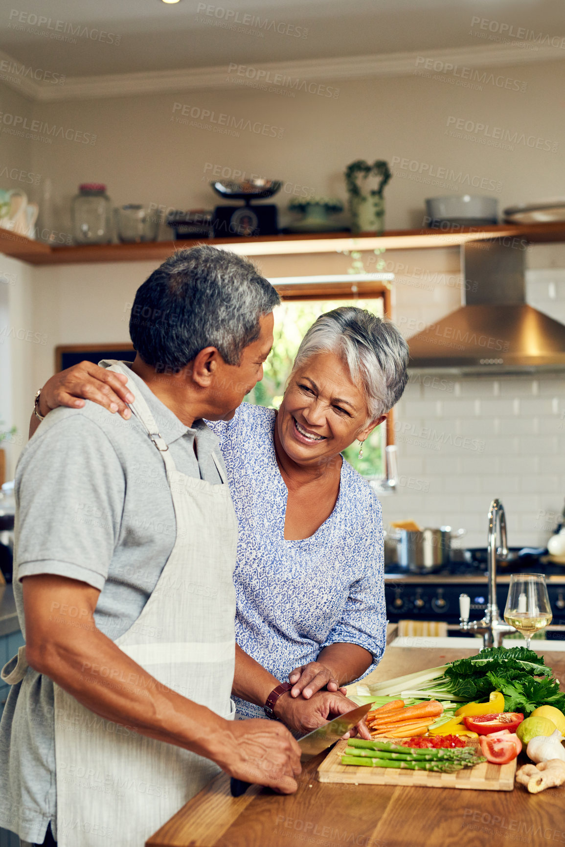 Buy stock photo Love, vegetables and old man with happy woman at kitchen counter, embrace and healthy marriage bonding in home. Happiness, help and cooking, senior couple with smile, hug and dinner in retirement.