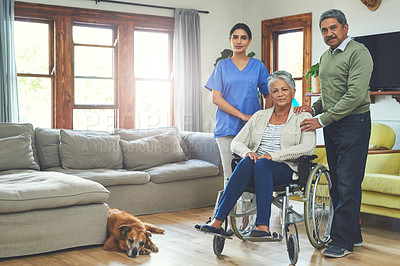 Buy stock photo Portrait of a cheerful woman seated in a wheelchair while being supported by her husband and a young female nurse inside at home