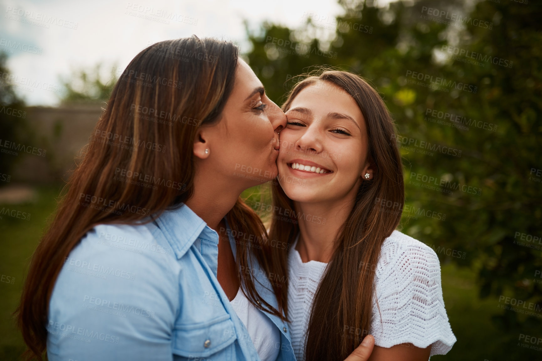 Buy stock photo Cropped shot of a young woman kissing her young daughter on the cheek