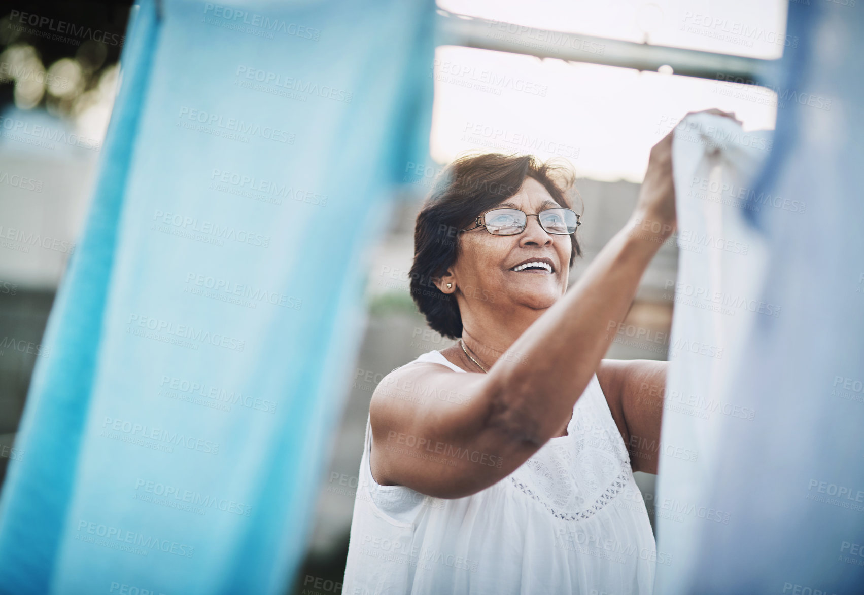 Buy stock photo Mature woman, clothesline and laundry in garden with household domestic chores, spring cleaning and housekeeping. Hanging clothes, fabric or white cotton sheet, cleaner and housework outdoor