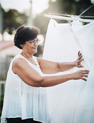 Buy stock photo Mature woman, clothesline and laundry outdoor with household domestic chores, spring cleaning and housekeeping. Hanging clothes, fabric or white cotton sheet, cleaner and housework with washing