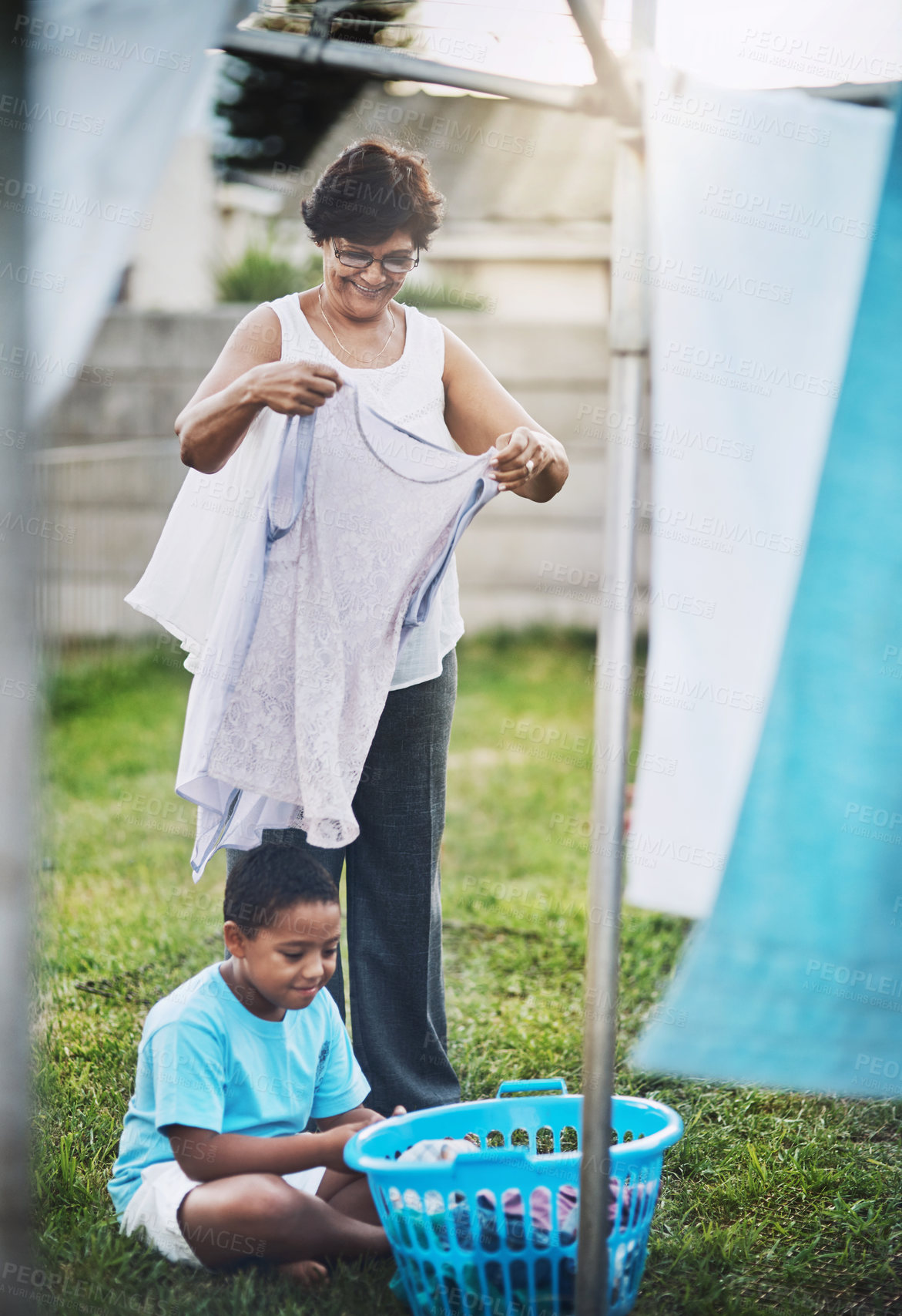 Buy stock photo Shot of a grandmother and her grandson hanging laundry together outdoors