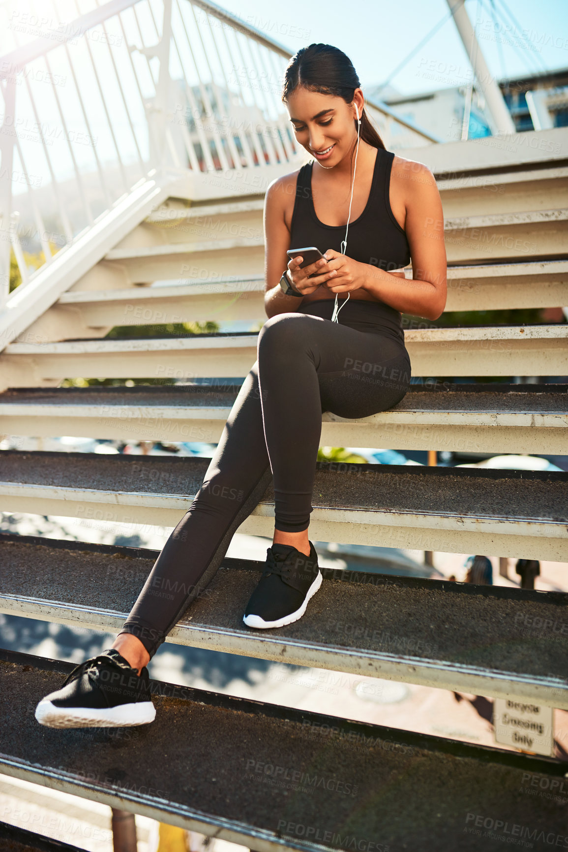 Buy stock photo Shot of a sporty young woman listening to music while exercising in the city