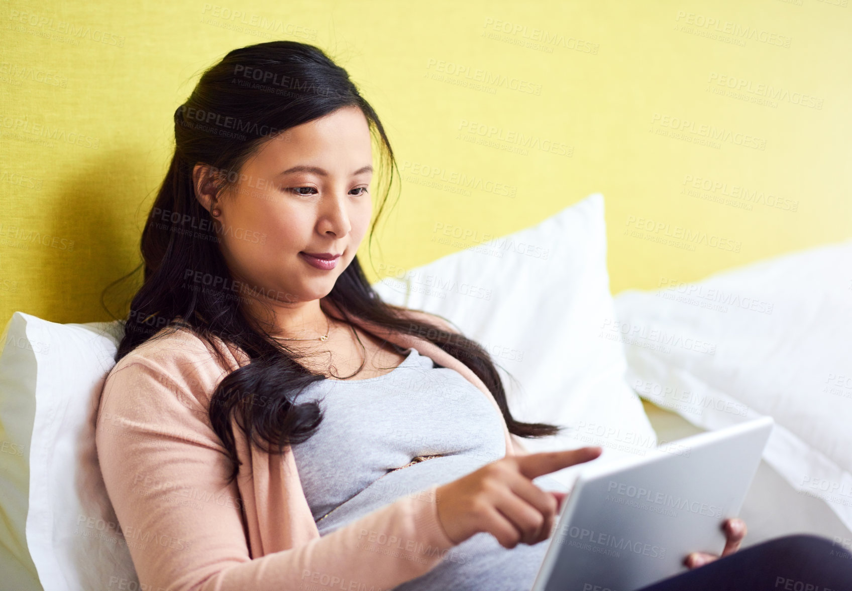 Buy stock photo Shot of a pregnant woman using a digital tablet at home