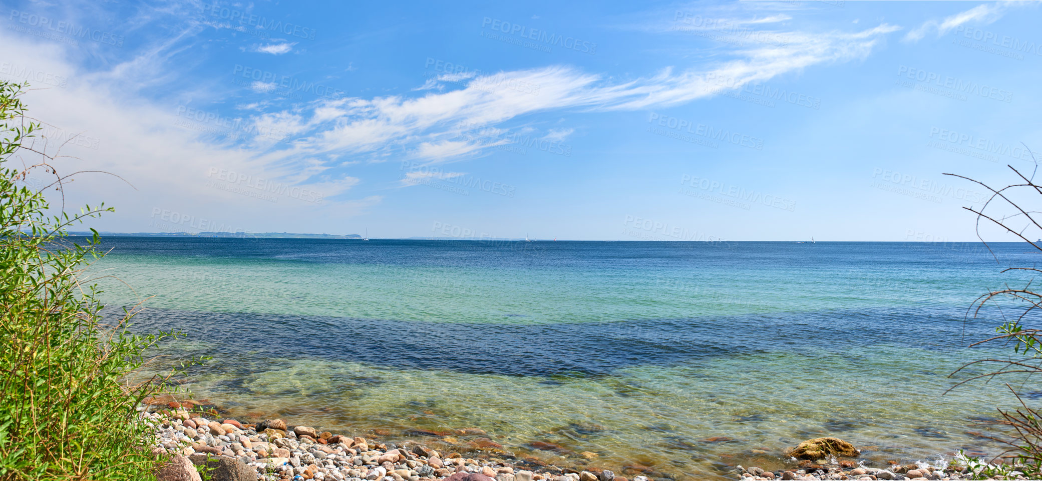 Buy stock photo Copy space at sea with a cloudy blue sky background across the horizon. Ocean waves washing onto stones at an empty beach shore. Peaceful scenic landscape for a relaxing and zen summer holiday 
