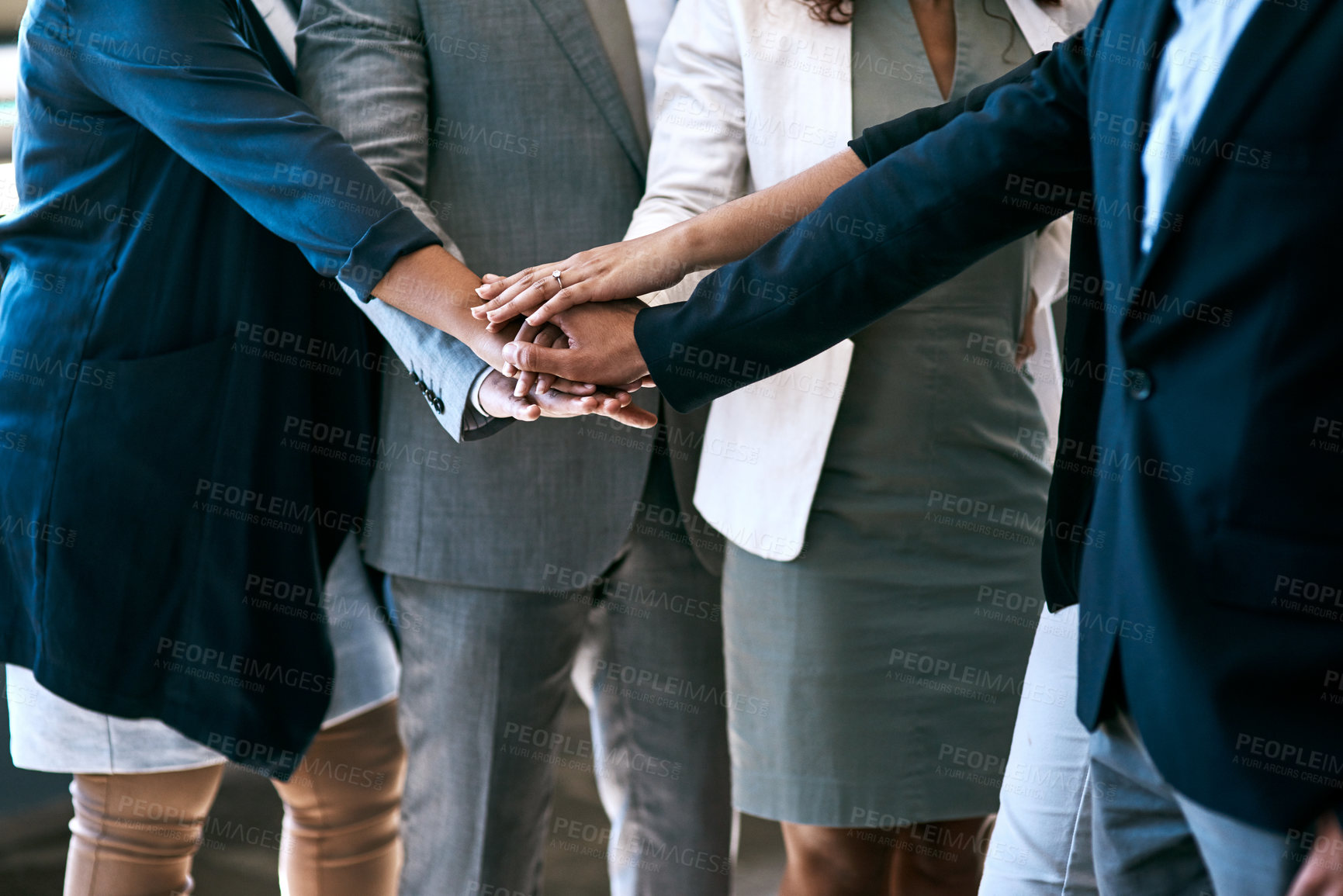 Buy stock photo Cropped shot of a group of unrecognizable businesspeople standing with their hands in a huddle in the office