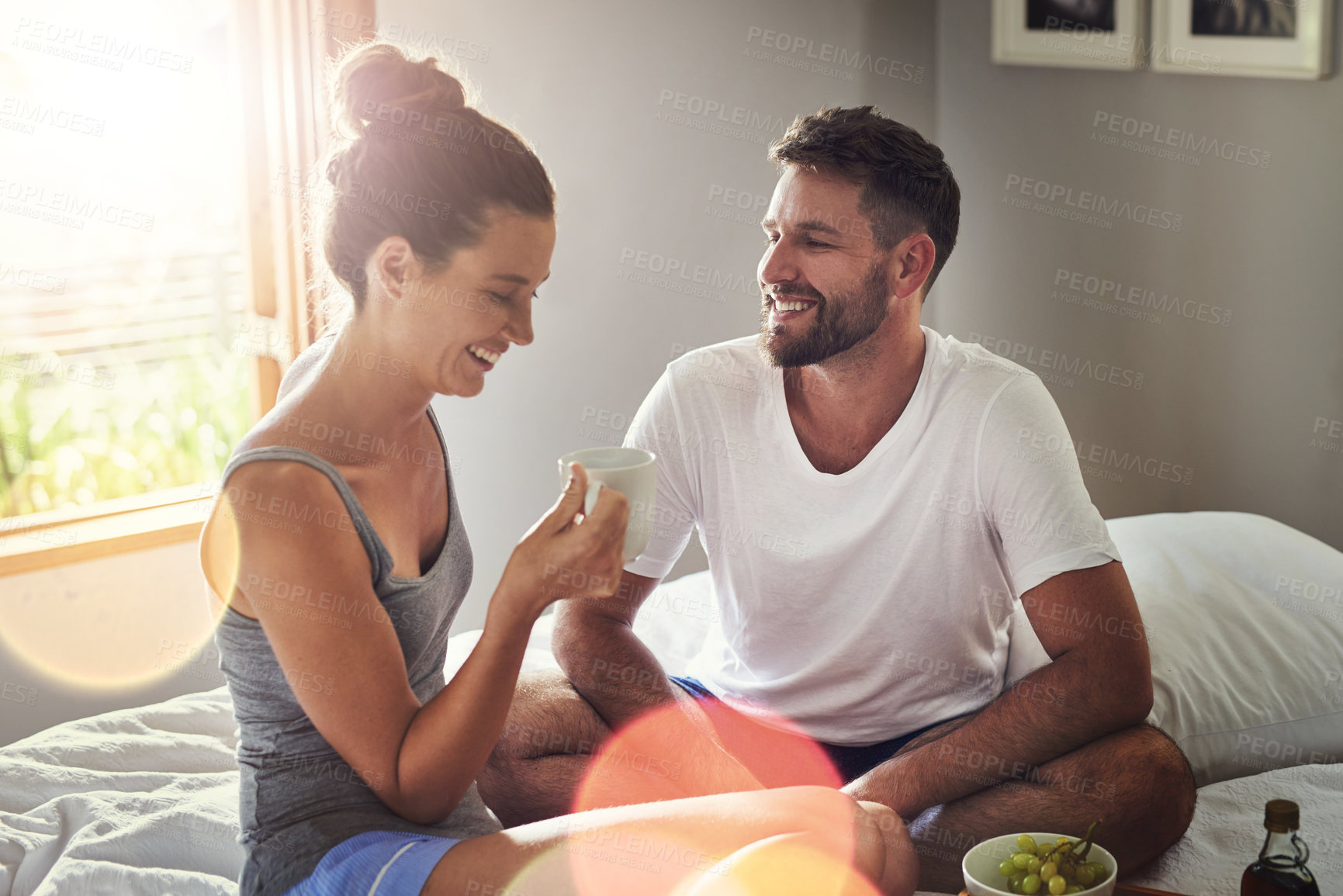 Buy stock photo Cropped shot of a happy young couple enjoying breakfast in bed together at home