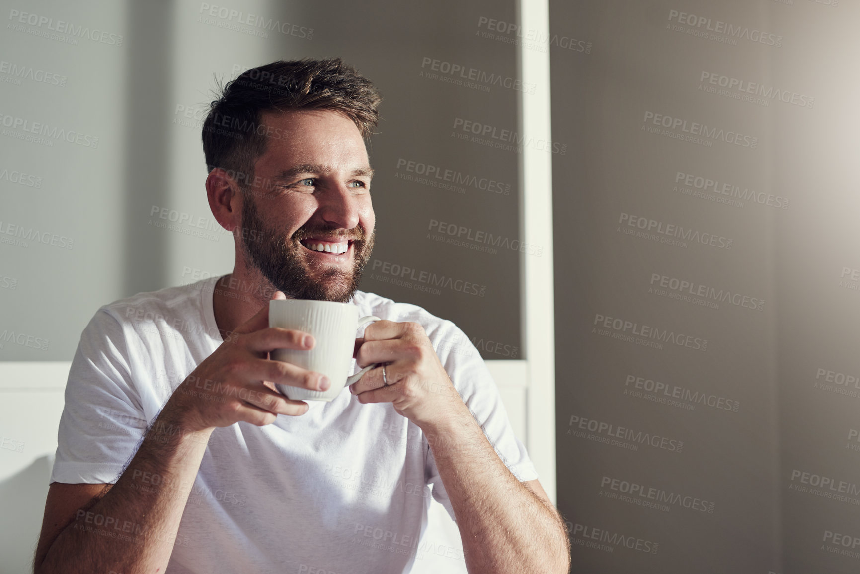 Buy stock photo Cropped shot of a handsome  young man drinking coffee in the bedroom at home