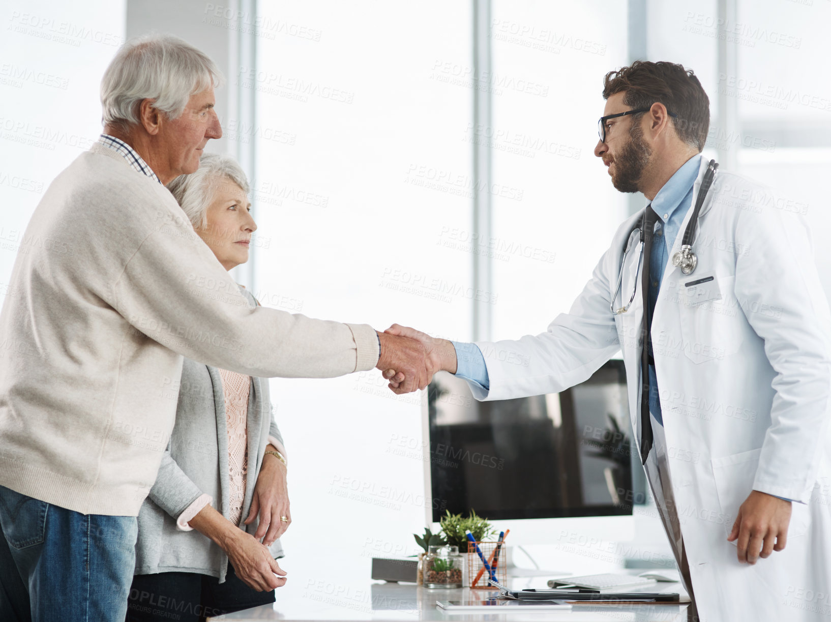 Buy stock photo Cropped shot of a confident young male doctor shaking a senior patient's hand after a consultation