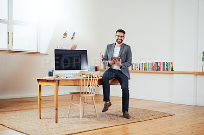 Buy stock photo Cropped portrait of a handsome young businessman working on a tablet while sitting in his home office