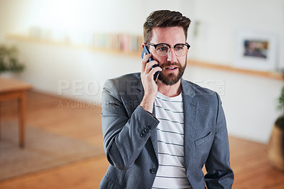 Buy stock photo Cropped shot of a handsome young businessman talking on his cellphone while standing in his home office