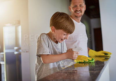 Buy stock photo Father, kid and cleaning table with spray in home for helping hand, teaching hygiene and bonding. Laughing, man and boy child with disinfectant to wipe surface in house for bacteria and chore support