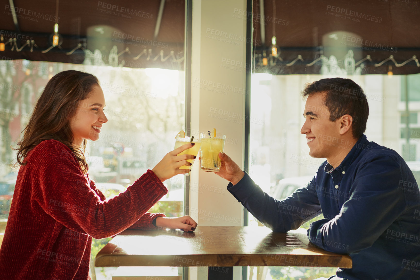 Buy stock photo Shot of a young man and woman toasting with their drinks on a romantic date at a coffee shop