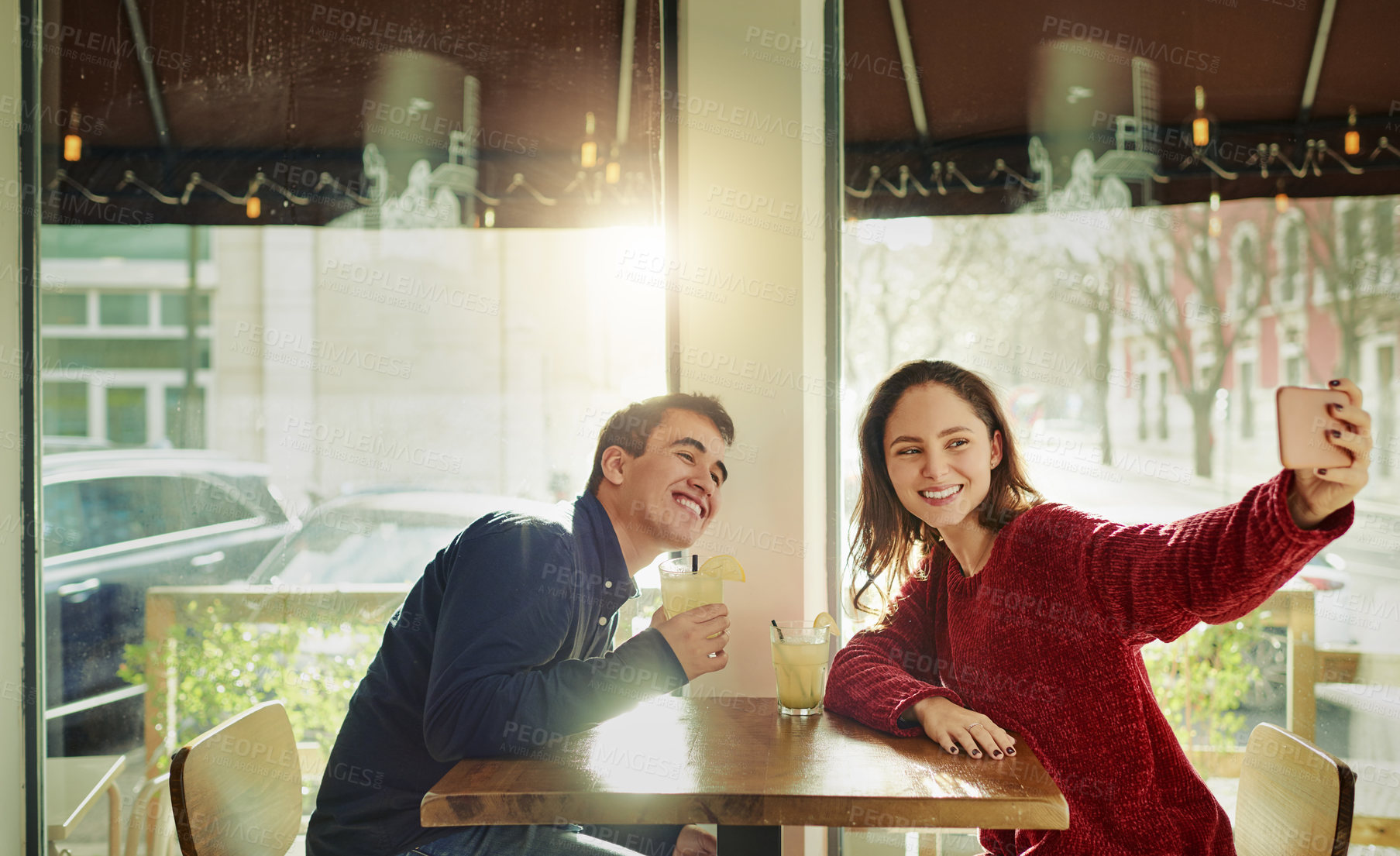 Buy stock photo Shot of a young man and woman taking selfies on a date at a coffee shop