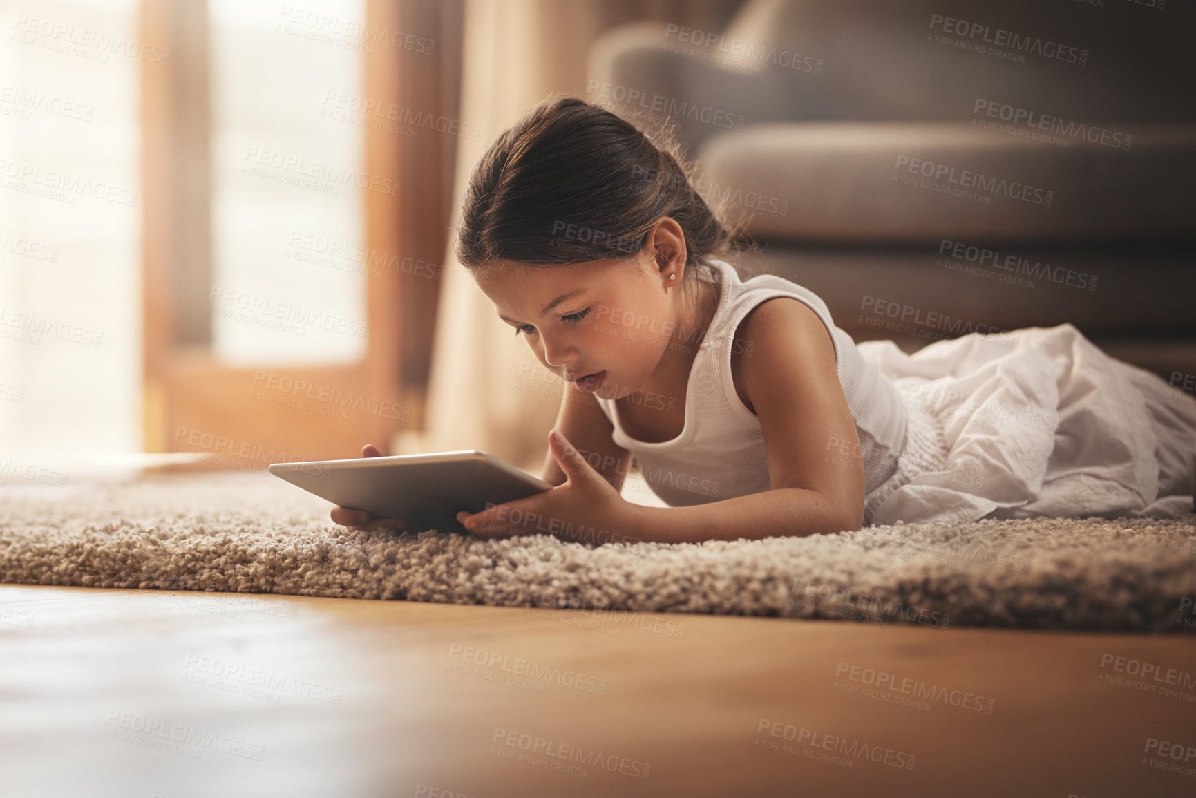 Buy stock photo Shot of an adorable little girl using a digital tablet on the floor at home