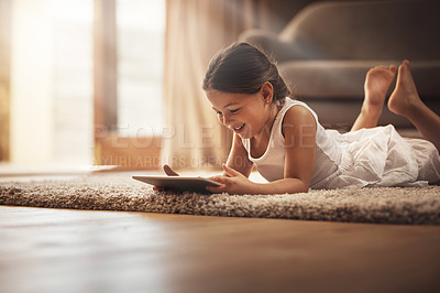 Buy stock photo Shot of an adorable little girl using a digital tablet on the floor at home
